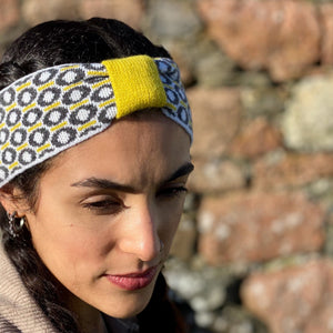 Woman wearing Scottish lambswool knitted headband with St Columba Iona halo motif charcoal and grey