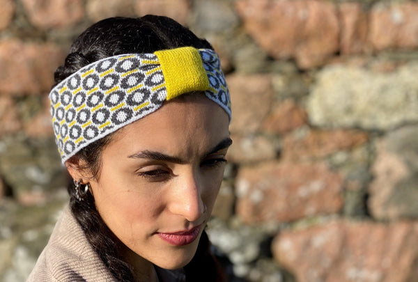 Woman wearing Scottish lambswool knitted headband with St Columba Iona halo motif charcoal and grey